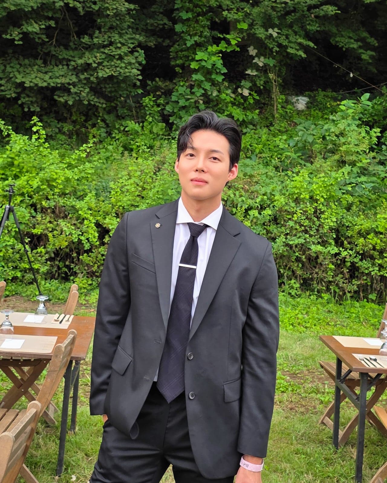 정장을 입고 야외 파티장에 서 있는 호스트 승후